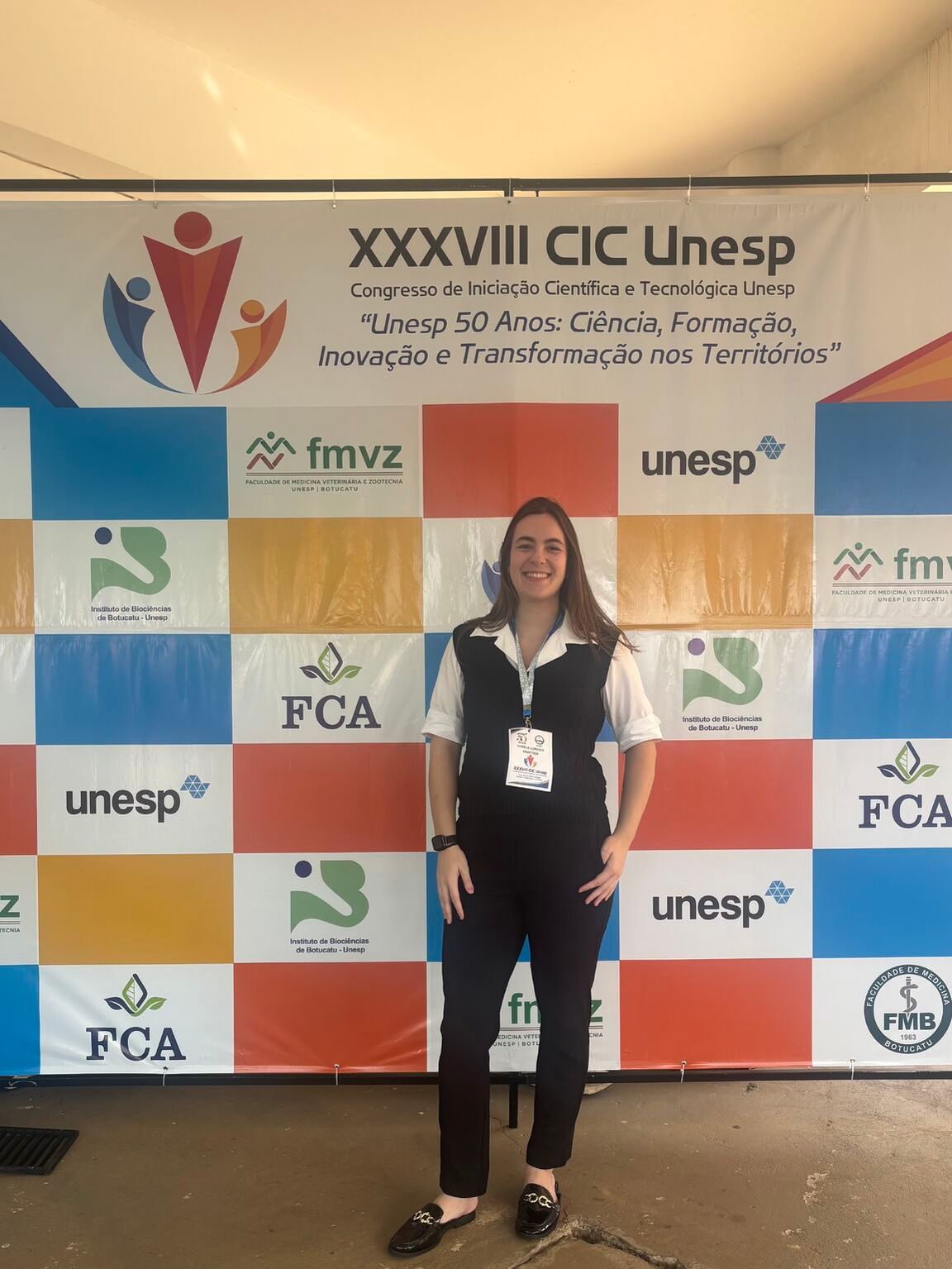 Isabela at the XXXVIII CIC Unesp backdrop, wearing her congress badge.