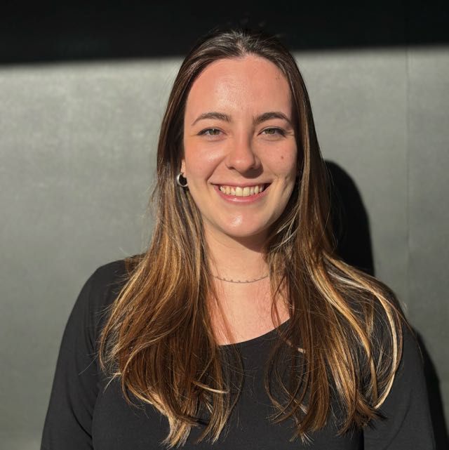 Isabela Lorente Kraetzer smiling in front of a grey wall.